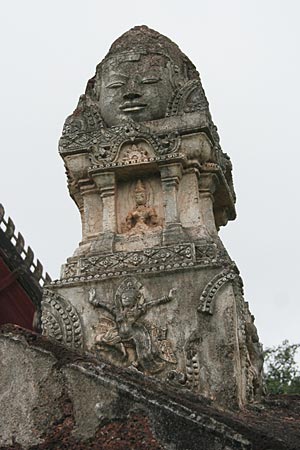 Above eastern gate to Wat Phra Sri Rattana Mahathat. Brahma head on top, niche with figurine, and Khmer-style heavenly female at bottom of decorative pillar